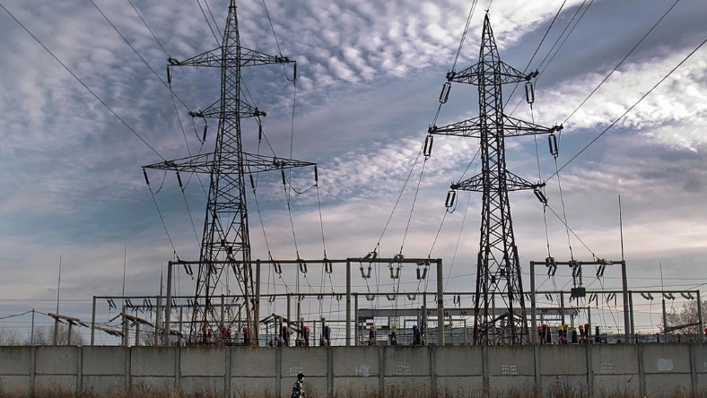 High-voltage transmission towers and substation infrastructure under cloudy sky